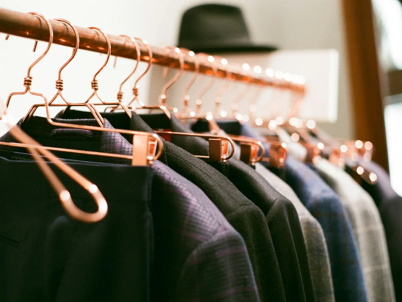 a rack of clothes with a hat on top of it