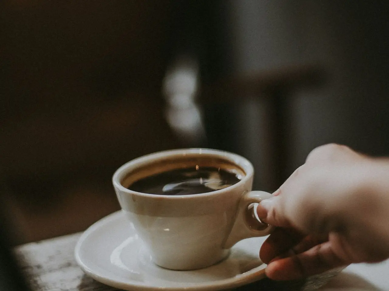 person holding white ceramic cup with liquid
